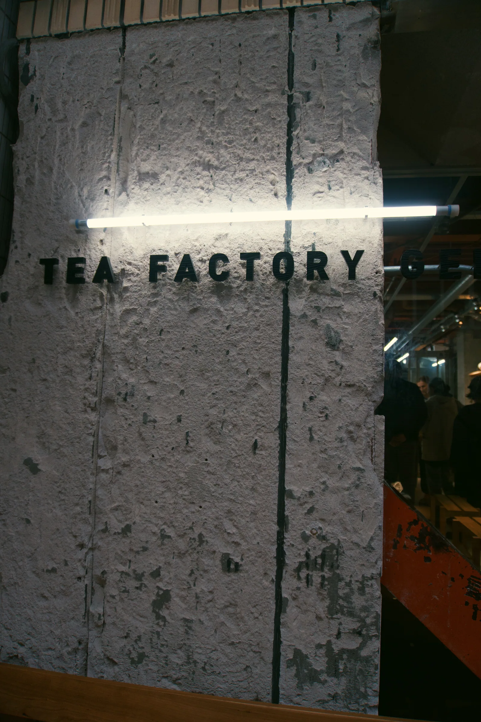 The words Tea Factory mounted on a concrete entrance wall