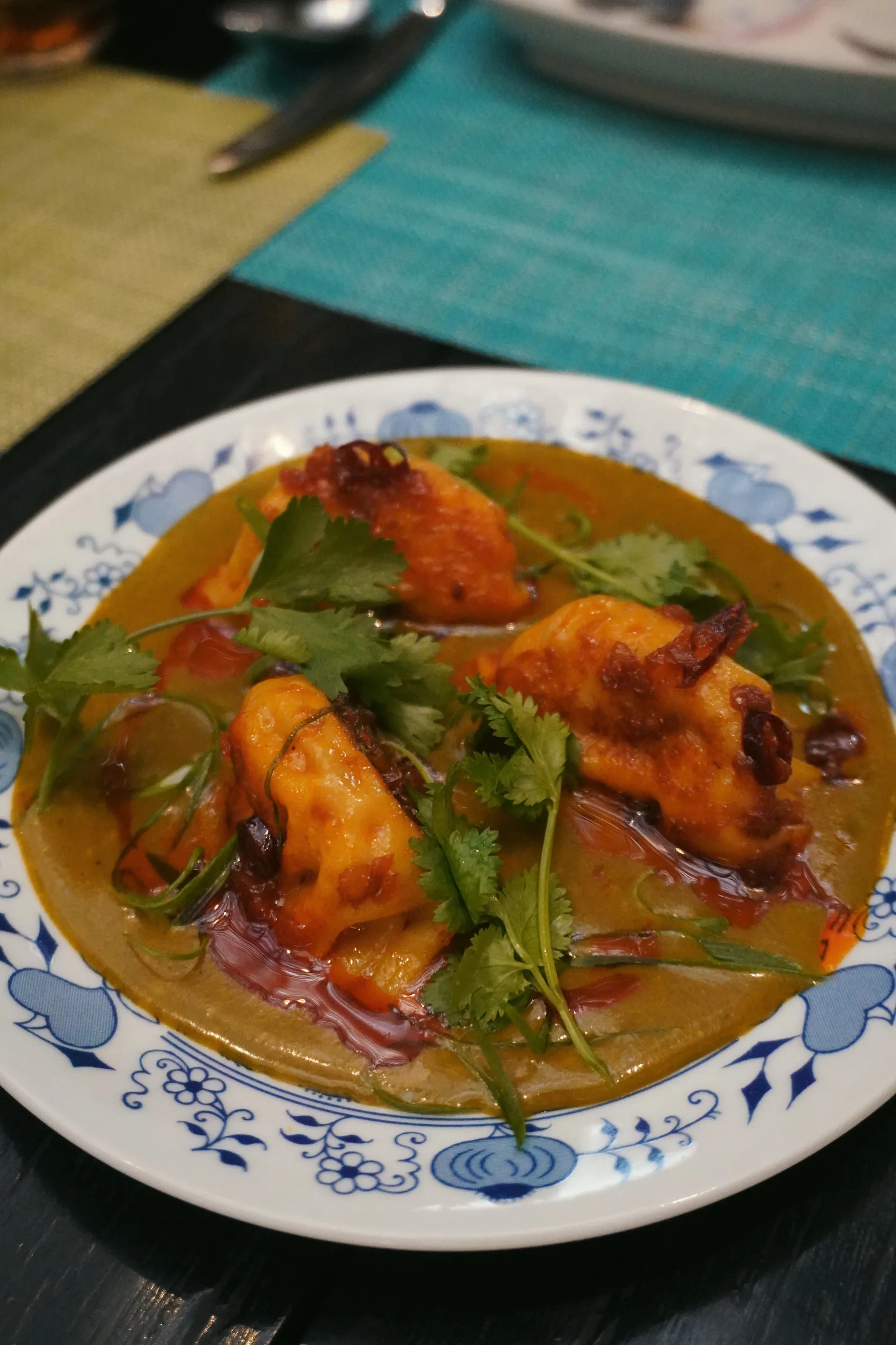 A seafood dish in orange broth with herbs on a patterned plate in Peru