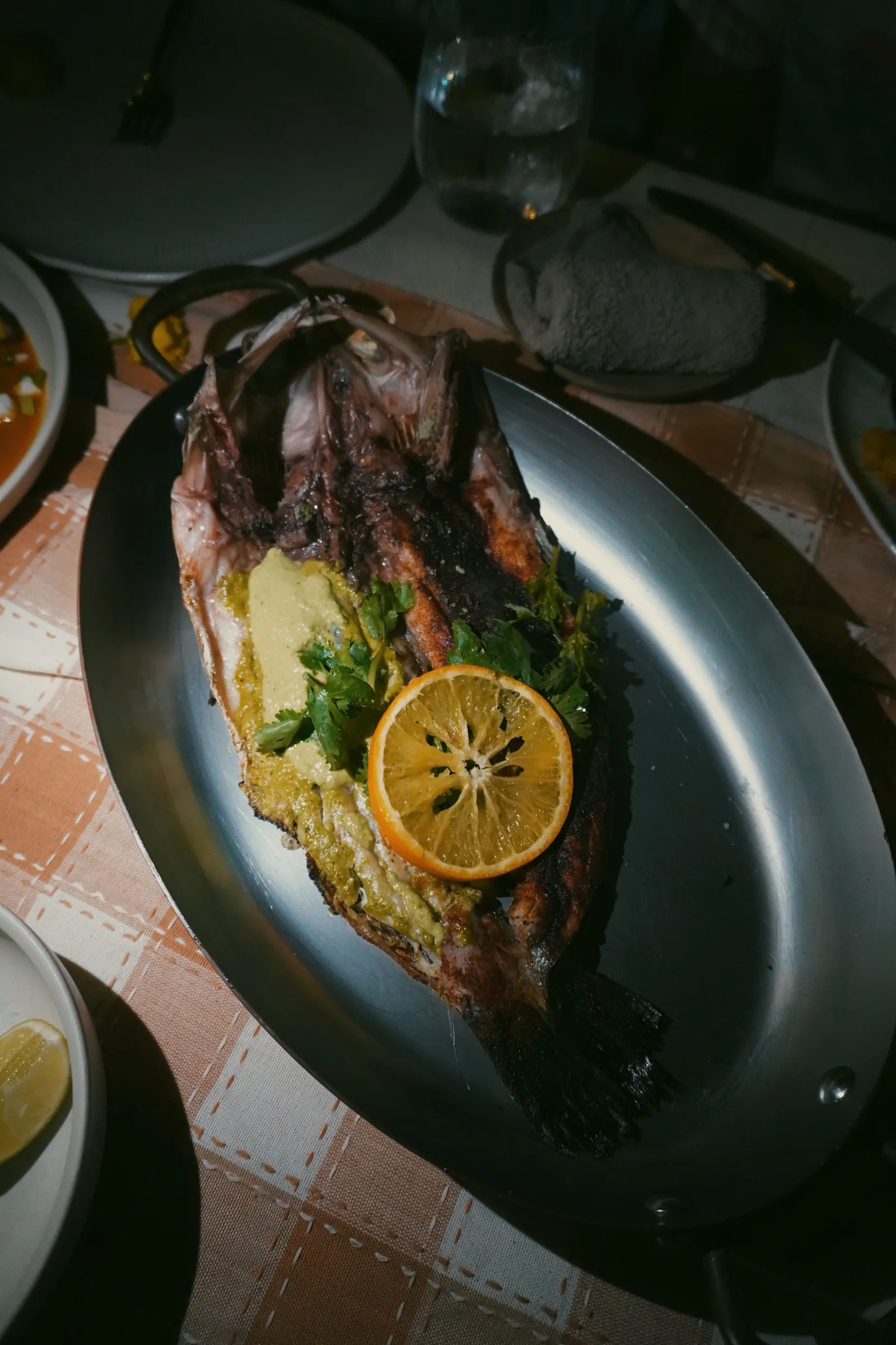 A whole cooked fish served with sliced citrus and herbs in Sumba